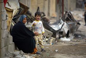 An Iraqi mother and her son sit amid the rubble