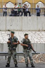 Hezbollah supporters look on as Lebanese army soldiers clear roadblocks along the highway leading to Beirut's airport.