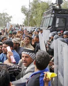 Iraqi riot police hold back an angry crowd in Basra